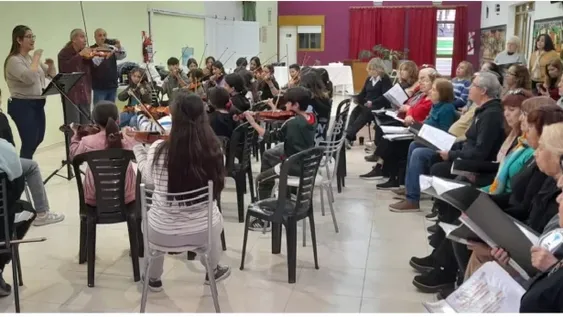 JUNTOS. Los chicos en sus sillas acompañados de sus instrumentos siguiendo la batuta de su director Rubén Carrillo y los adultos mayores poniendo sus voces, a la par.