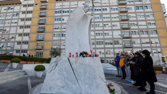 Rezo y esperanza. Varias personas ante la estatua de Juan Pablo II situada frente al hospital Gemelli de Roma, donde está ingresado el Papa. Foto: El País de España