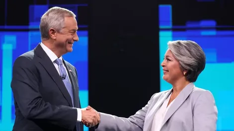Jeannette Jara, presidential candidate representing Chiles ruling leftist coalition and a member of the Communist Party, and Jose Antonio Kast of the far-right Republican Party, shake hands as they attend the last televised debate before the December 14 election, in Santiago, Chile, December 9, 2025. REUTERS/Pablo Sanhueza