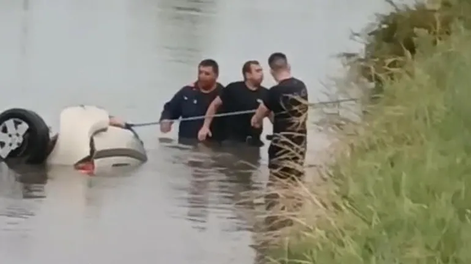 Bomberos intentan rescatar el auto.