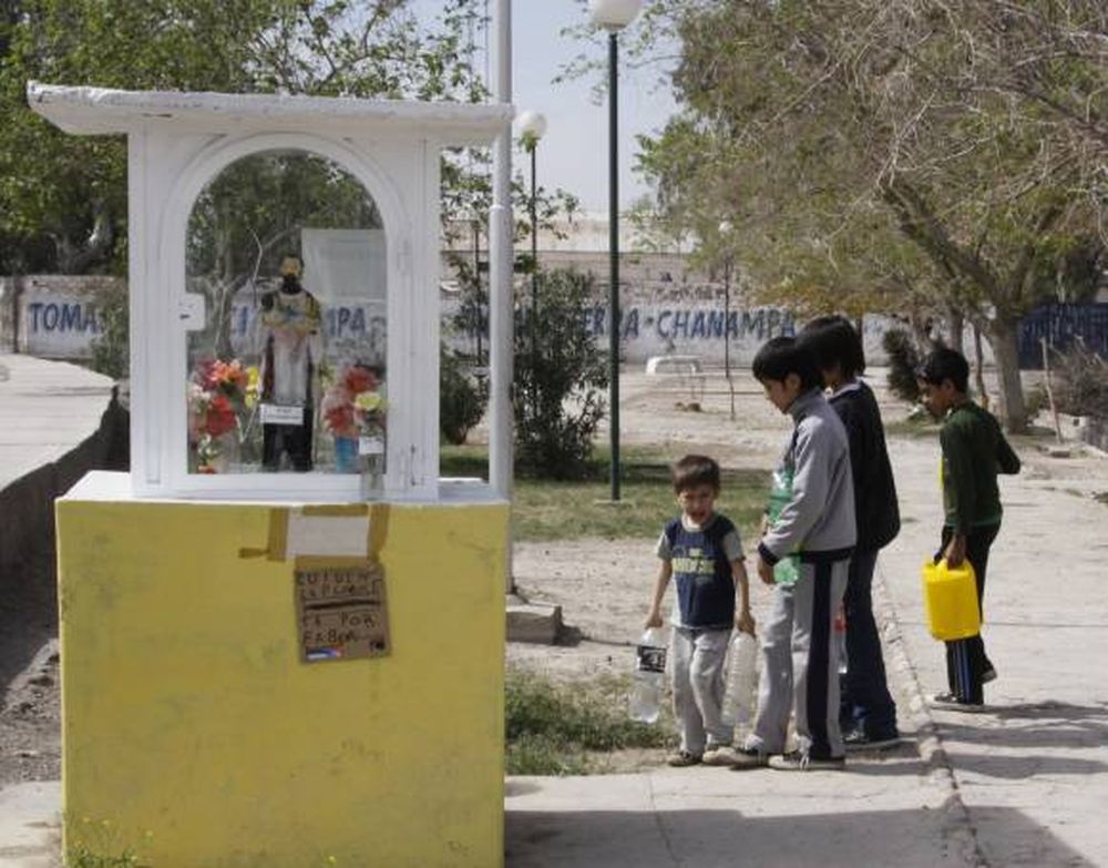 Los niños que acarrean agua en  botellas para regar una plazoleta