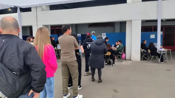 Todo el color de las elecciones en el centro de votación más grande de Santiago de Chile: largas filas, mucha prensa, mascotas y hasta un Grinch