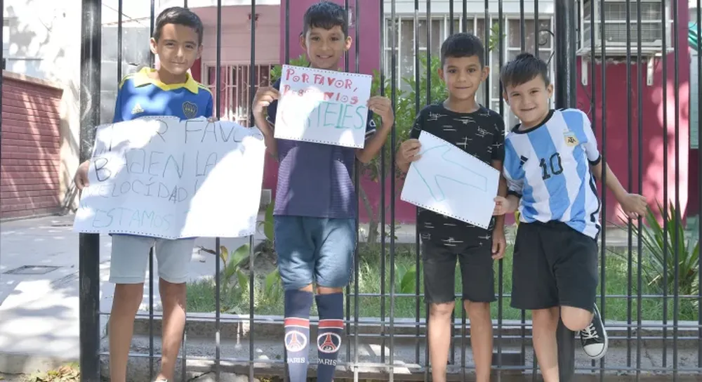 Niños que salieron a pegar carteles para que los autos bajen la velocidad