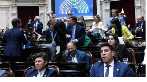 PUÑOS EN ALTO. Diputados libertarios festejan la votación que blindó el acuerdo con el FMI tras una sesión caliente con gritos e insultos de los legisladores.