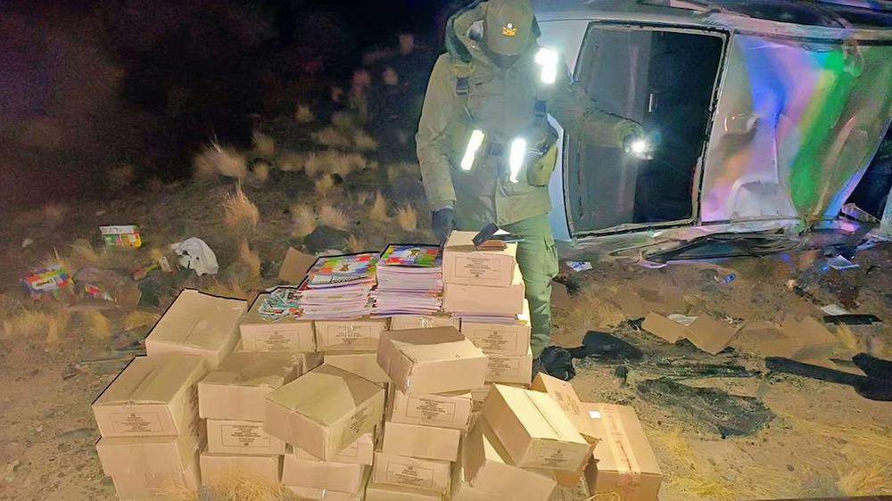 Un agente de seguridad examina el cargamento de álbumes y figuritas del Mundial 2026 hallado tras el accidente vehicular.